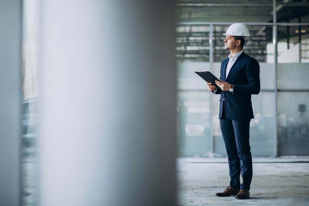Profissional de imigração USA com capacete, analisando projeto de engenharia.